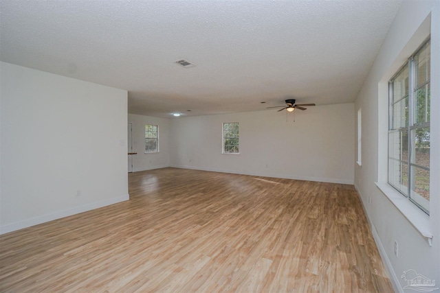 unfurnished room with ceiling fan, plenty of natural light, a textured ceiling, and light wood-type flooring