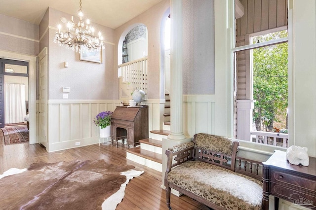 living area featuring a wainscoted wall, stairway, a chandelier, and hardwood / wood-style flooring