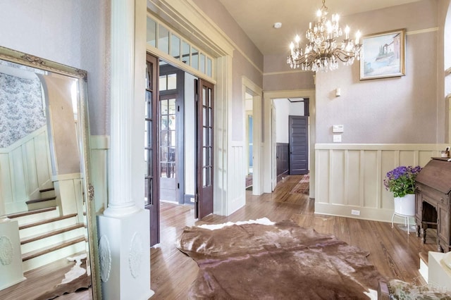 entrance foyer featuring stairs, wainscoting, wood finished floors, and a chandelier