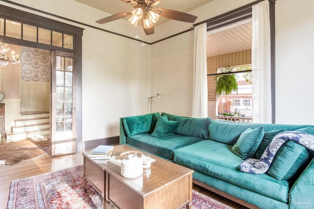 living room with stairs, ceiling fan with notable chandelier, and wood finished floors