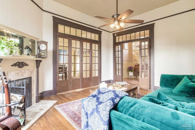 living area with french doors, a tiled fireplace, wood finished floors, and a ceiling fan