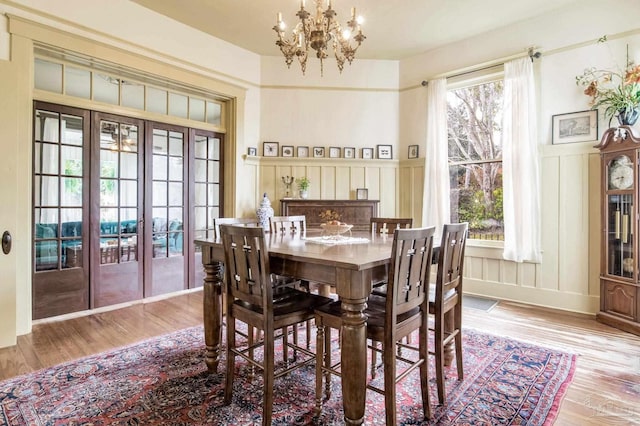 dining area featuring an inviting chandelier, plenty of natural light, a decorative wall, and wood finished floors