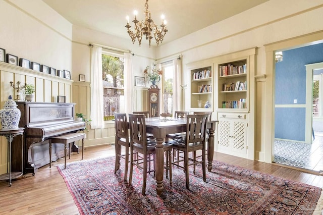 dining area with baseboards, built in shelves, wood finished floors, and a notable chandelier