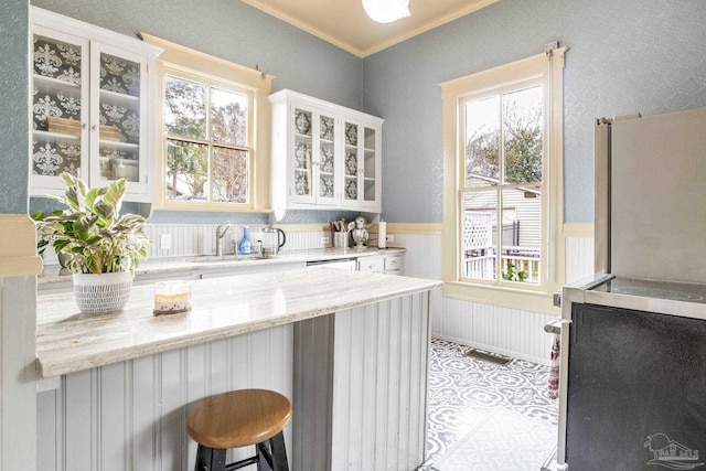 bar featuring a wainscoted wall, a sink, and crown molding