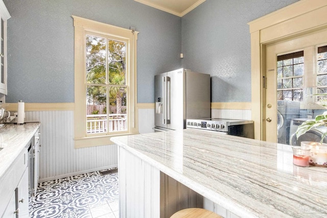 kitchen featuring a wainscoted wall, stainless steel appliances, ornamental molding, and a wealth of natural light