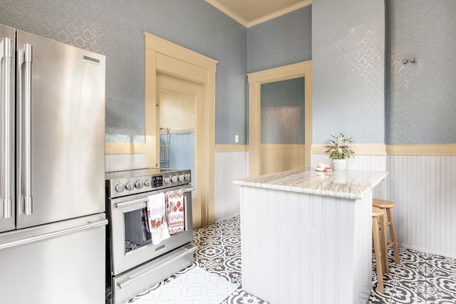 kitchen featuring a wainscoted wall, ornamental molding, stainless steel appliances, and wallpapered walls