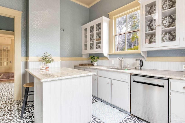 kitchen with a sink, white cabinetry, stainless steel dishwasher, a center island, and wallpapered walls