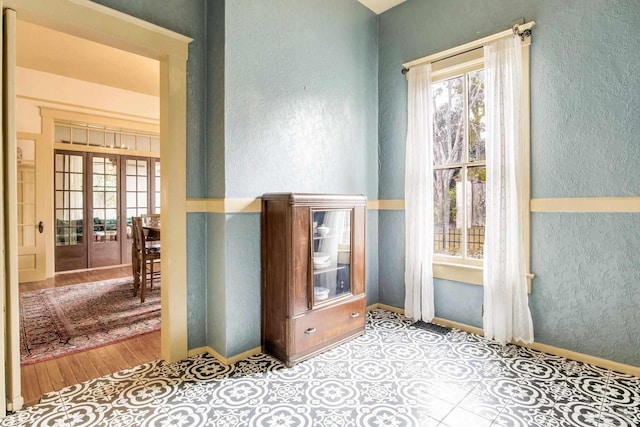 empty room with a textured wall, french doors, and baseboards