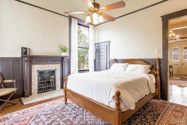 bedroom with a fireplace with raised hearth, wood finished floors, and crown molding