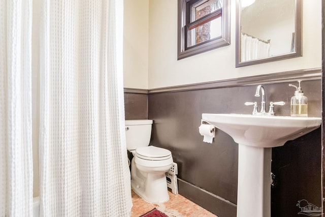 bathroom featuring a wainscoted wall, a shower with shower curtain, toilet, and a bath