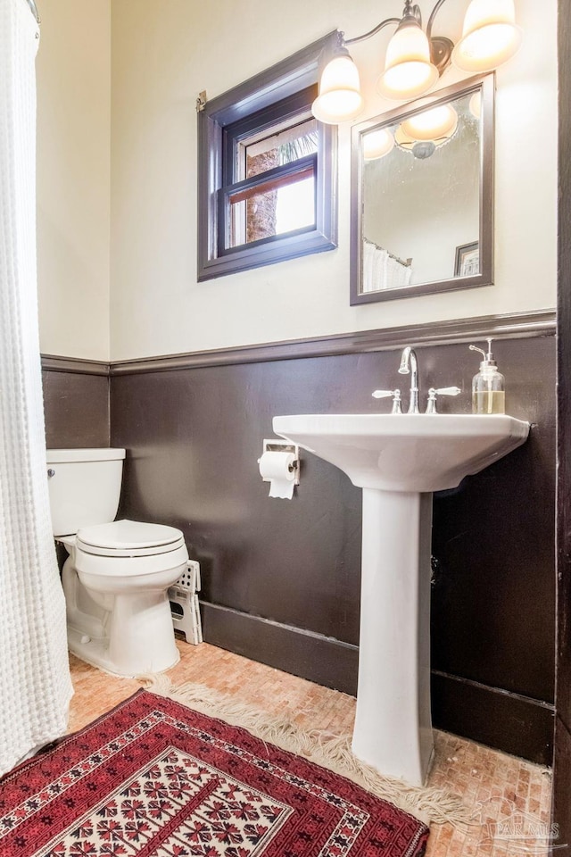 bathroom with a wainscoted wall and toilet