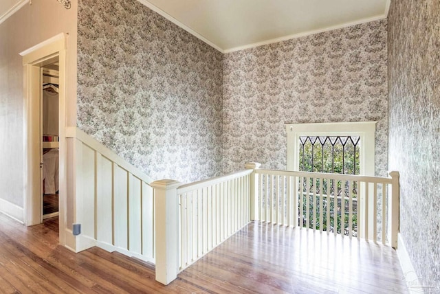 interior space featuring ornamental molding, wood finished floors, and wallpapered walls