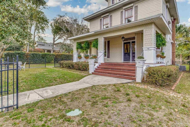 american foursquare style home with covered porch, fence, and a front lawn