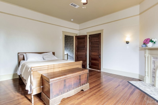 bedroom with crown molding, visible vents, light wood-style flooring, a high end fireplace, and baseboards