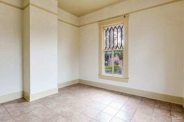 spare room featuring a healthy amount of sunlight, light tile patterned floors, and baseboards