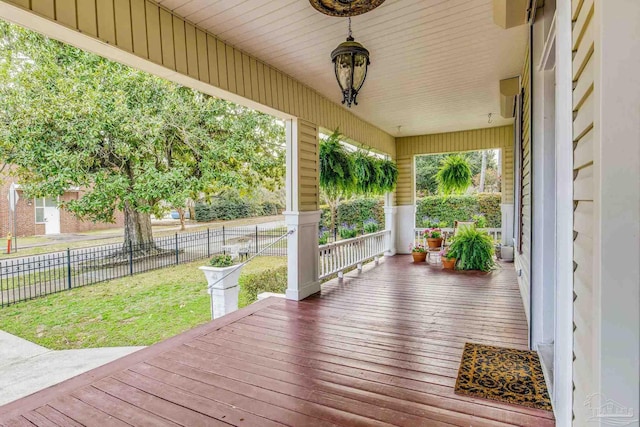 wooden terrace with covered porch, a lawn, and fence