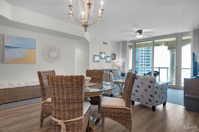 dining space with ceiling fan with notable chandelier and wood-type flooring