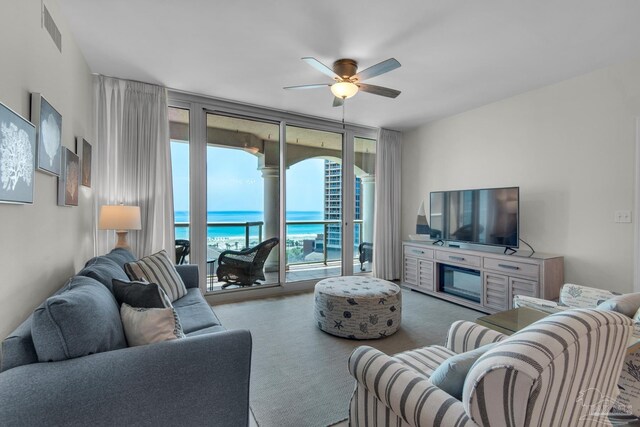 carpeted living room with ceiling fan and expansive windows