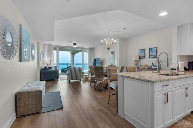 kitchen featuring white cabinetry, ceiling fan with notable chandelier, sink, and light hardwood / wood-style flooring