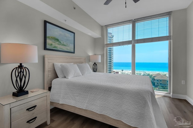 bedroom featuring ceiling fan, dark hardwood / wood-style floors, and a water view