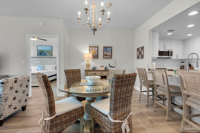 dining area featuring sink, ceiling fan with notable chandelier, and light hardwood / wood-style floors