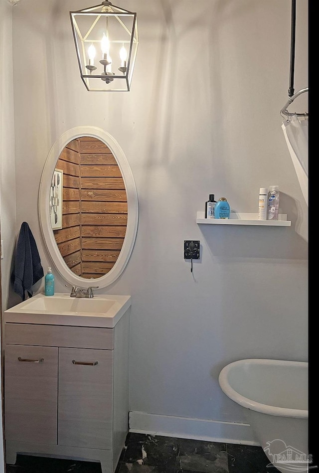 bathroom with a freestanding bath, baseboards, a notable chandelier, and vanity