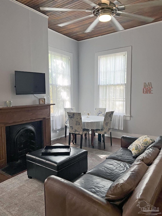 living room with a ceiling fan, a wealth of natural light, wooden ceiling, and a fireplace with flush hearth