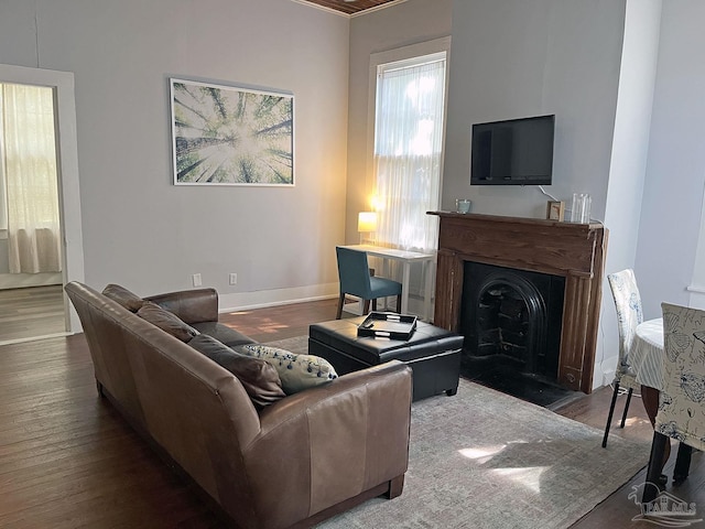 living room featuring a fireplace with flush hearth, baseboards, and wood finished floors