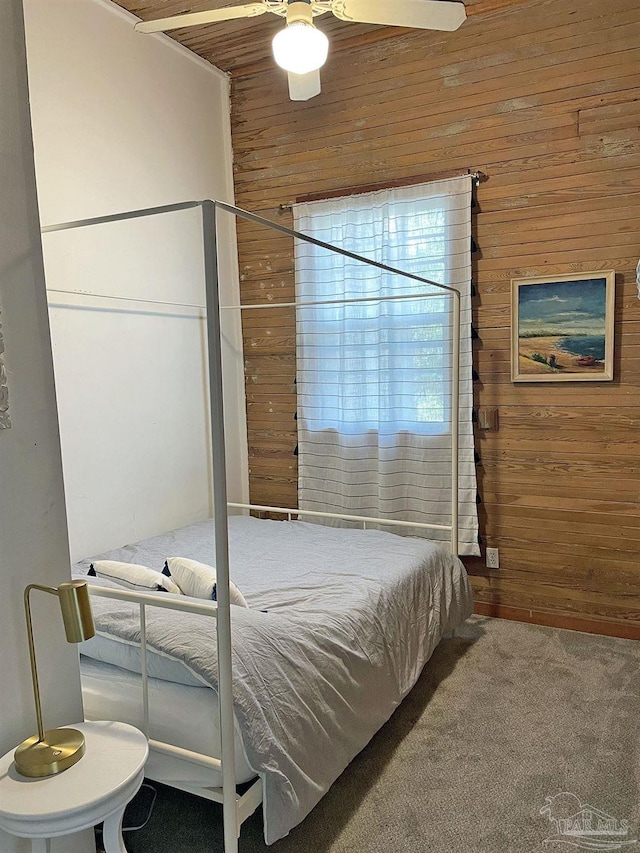 carpeted bedroom with wood walls and a ceiling fan