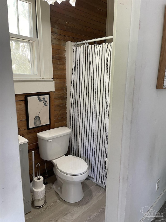 bathroom featuring toilet, wood walls, wood finished floors, vanity, and a shower with curtain