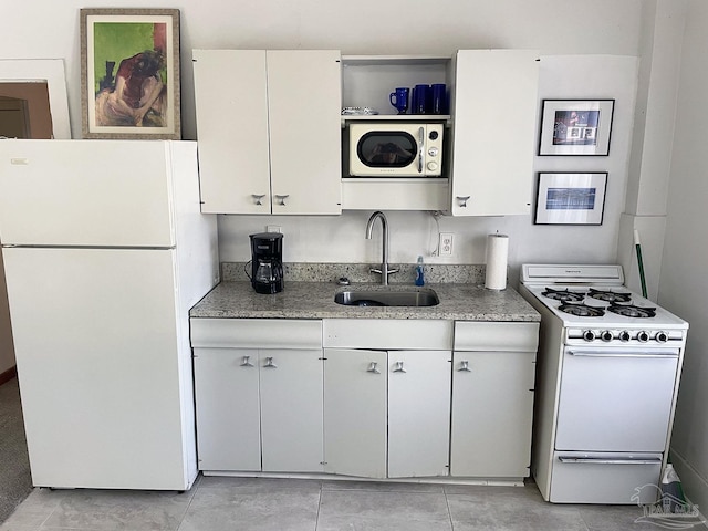 kitchen with open shelves, white cabinetry, a sink, light stone countertops, and white appliances