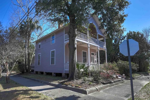 view of home's exterior featuring a porch, a chimney, and a balcony