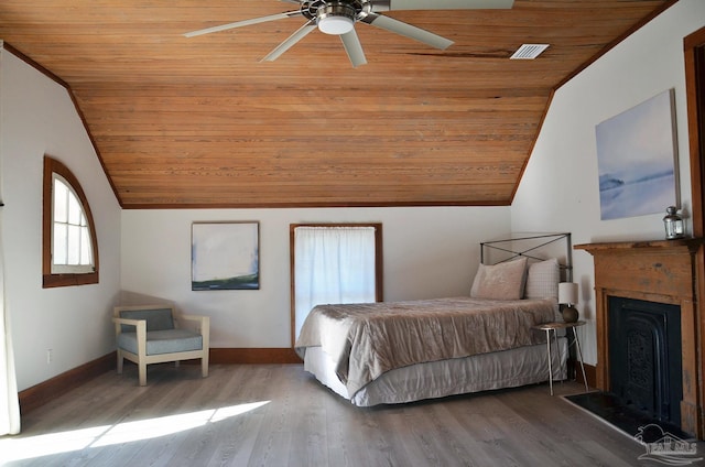 bedroom featuring baseboards, wooden ceiling, wood finished floors, vaulted ceiling, and a fireplace