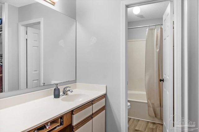 full bathroom with wood-type flooring, a textured ceiling, toilet, vanity, and shower / tub combo