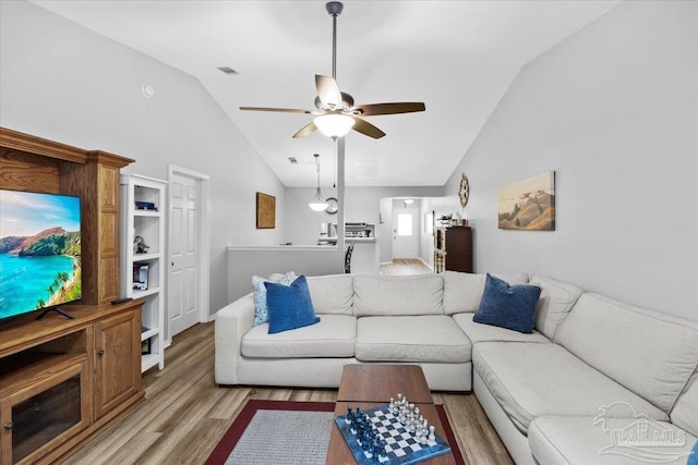 living room with light hardwood / wood-style flooring, vaulted ceiling, and ceiling fan