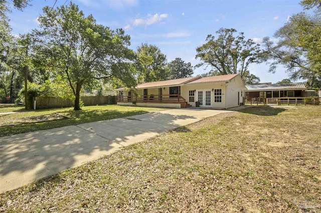 back of property with fence, metal roof, a lawn, and french doors