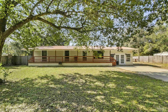 rear view of house featuring a yard, fence, and french doors