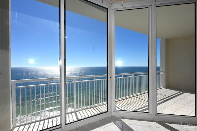 interior space with a healthy amount of sunlight, a water view, and a view of the beach