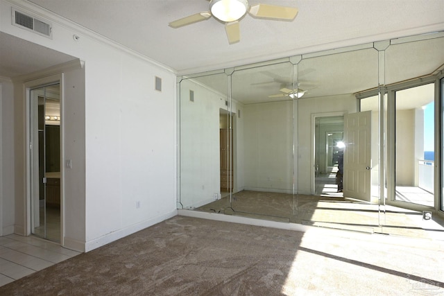 empty room featuring carpet floors, ceiling fan, and crown molding