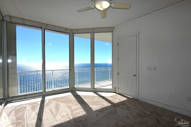 carpeted spare room featuring ceiling fan, crown molding, and a water view