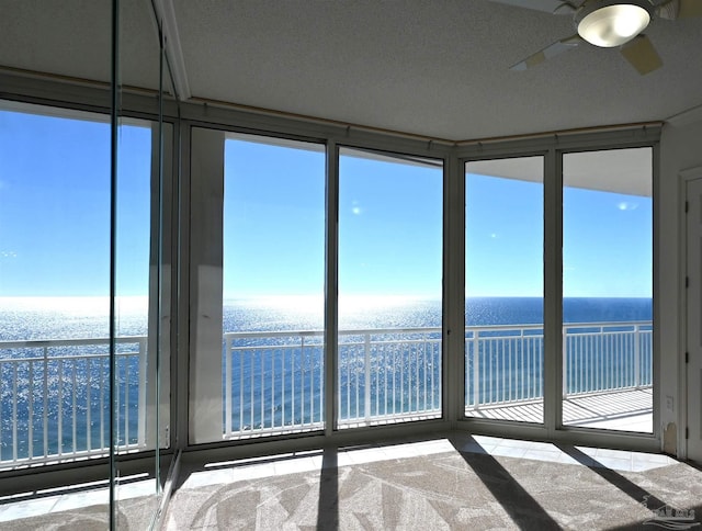 unfurnished sunroom with a water view and ceiling fan