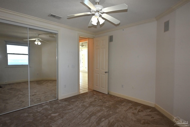 unfurnished bedroom featuring carpet, a closet, ceiling fan, and ornamental molding