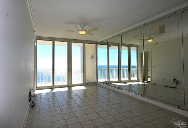 tiled empty room featuring floor to ceiling windows, a water view, ceiling fan, and crown molding