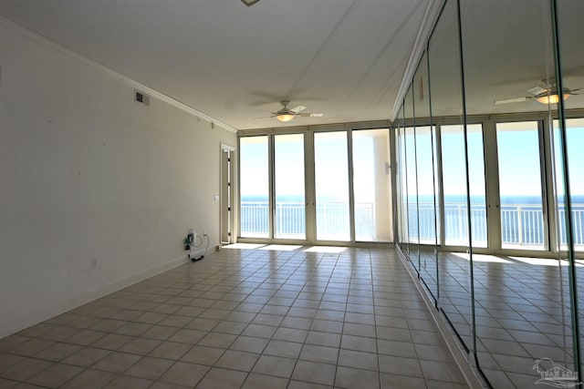 empty room featuring a water view, ceiling fan, and expansive windows