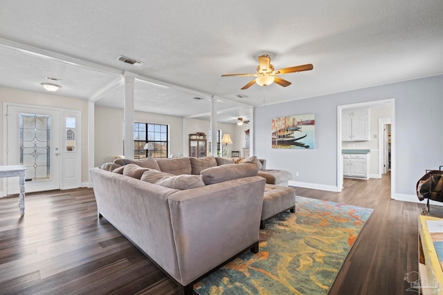 living room featuring decorative columns, ceiling fan, dark hardwood / wood-style floors, and a textured ceiling