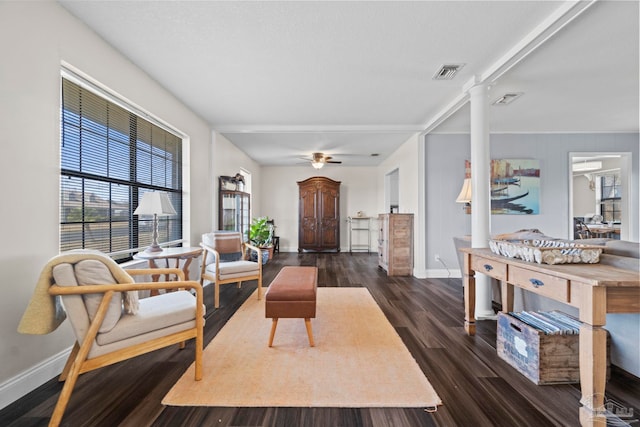 living room featuring dark wood-type flooring, ceiling fan, and decorative columns