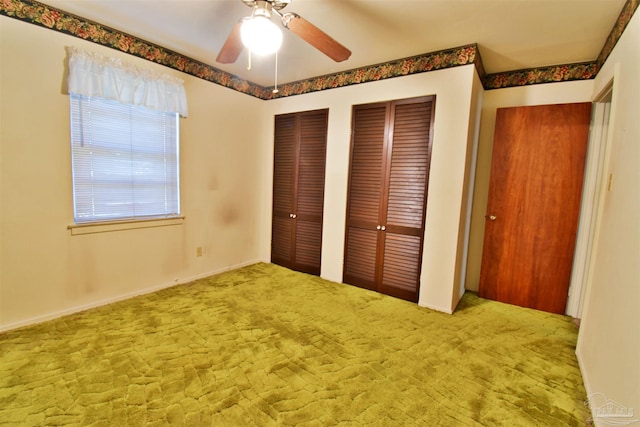 unfurnished bedroom featuring multiple closets, carpet floors, and ceiling fan