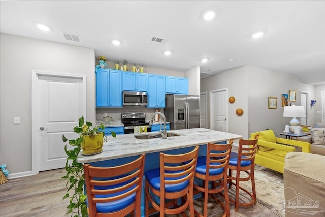 138 Georgia St, Crestview, FL 32536 - kitchen with appliances with stainless steel finishes, blue cabinetry, a sink, a kitchen breakfast bar, and light wood finished floors