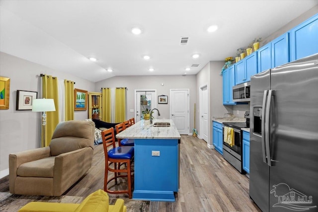 138 Georgia St, Crestview, FL 32536 - kitchen with stainless steel appliances, open floor plan, blue cabinetry, a breakfast bar area, and light wood-style flooring