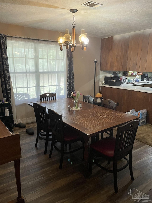 dining room with dark hardwood / wood-style flooring, a textured ceiling, and a chandelier